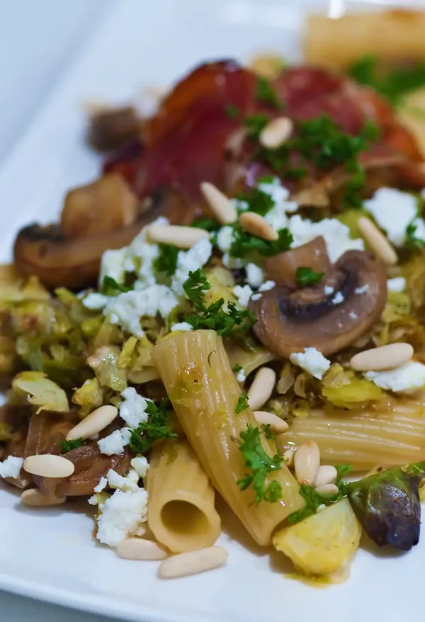 Rigatoni mit geröstetem Rosenkohl, gebratenen Champignons und Feta mit Zitrone, Speck und Pinienkernen